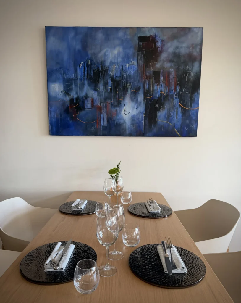 Cité imaginaire dans des tons bleus, huile sur toile de Remy de Polignac, au-dessus d'une table du restaurant